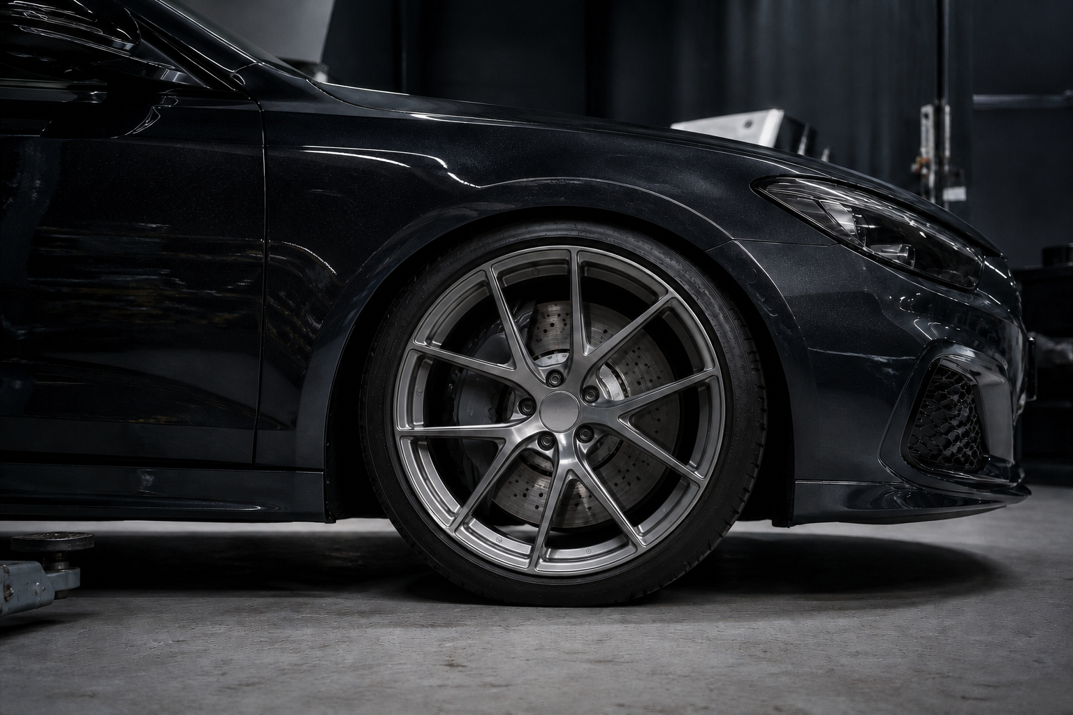 Detailaufnahme einer dunklen Performance-Felge mit Reifen und Kotflügel